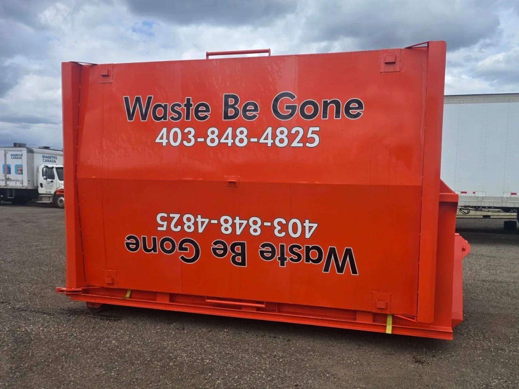 Bright orange waste container with contact information for 'Waste Be Gone'.