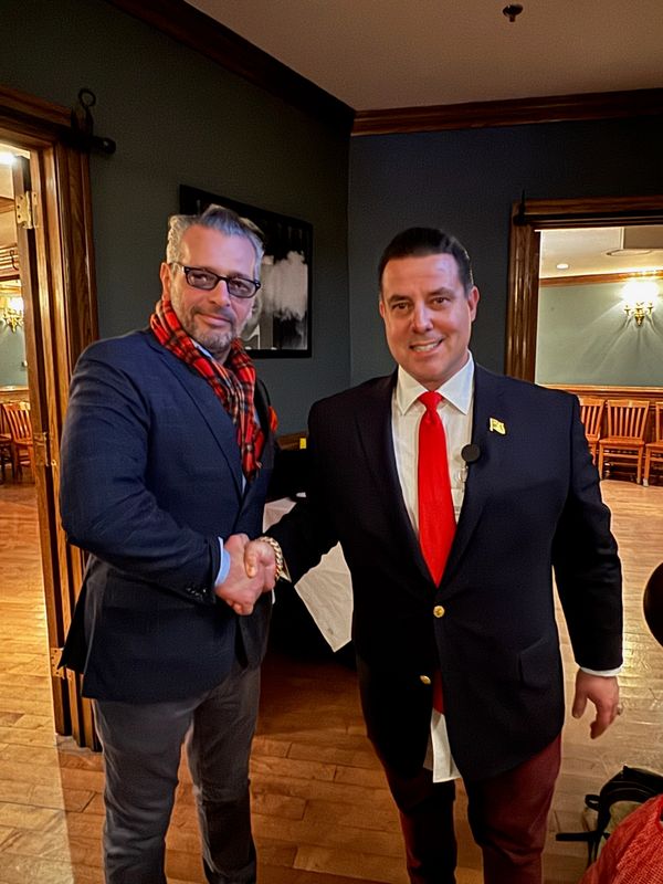 Two men in suits shaking hands indoors.