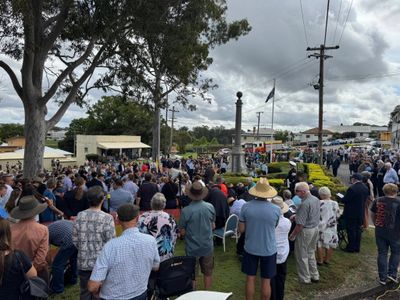 Crowd gathered outdoors around a monument on a cloudy day.