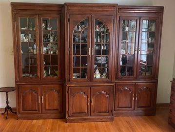 Wooden display cabinet with glass doors showcasing decorative items.