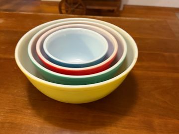 A set of colorful nested mixing bowls on a wooden table.
