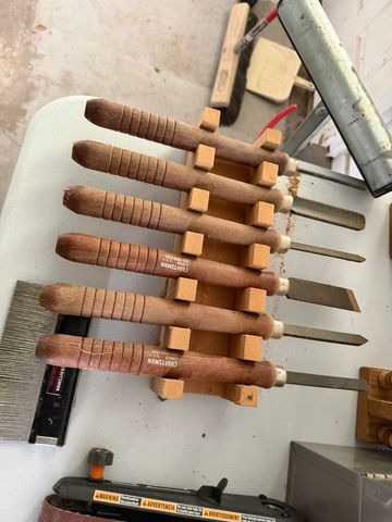 Set of woodworking chisels with wooden handles organized on a table.