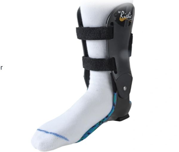 Black ankle brace with straps on a foot wearing a white sock.