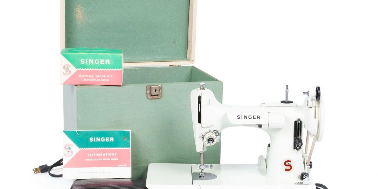 Vintage Singer Featherweight portable sewing machine with accessories and carrying case.