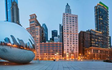 The Cloud Gate sculpture in Chicago reflecting city buildings at dusk.