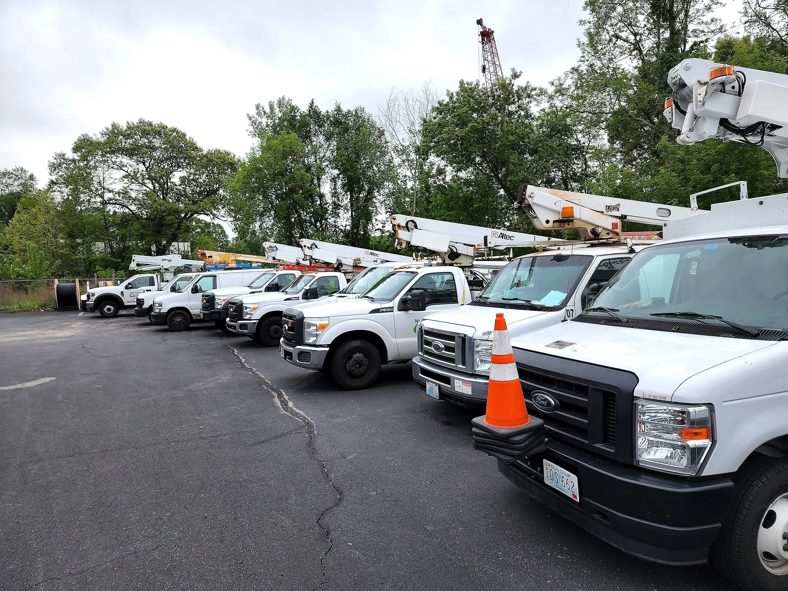 A row of white utility bucket trucks parked outdoors.