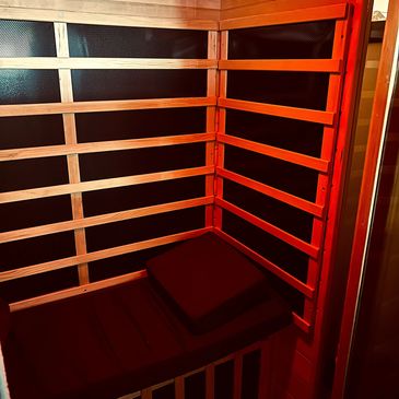Cozy wooden sauna interior with a bench and pillow under warm lighting.
