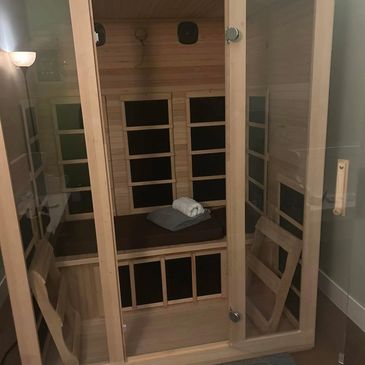 A cozy wooden sauna with a glass door and folded towels inside.