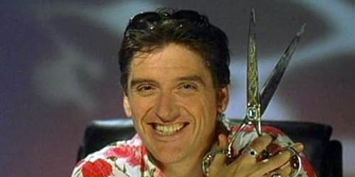 Man smiling while holding large scissors.