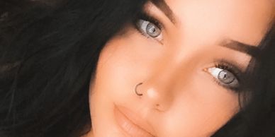 Close-up of a woman with striking blue eyes and a nose ring.