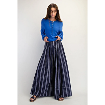 Young woman in a blue top and striped wide-leg pants.