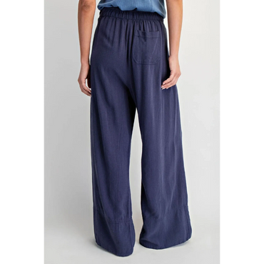 Woman wearing loose navy blue wide-leg pants with an elastic waistband and a back pocket.