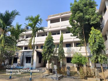 White multi-story building surrounded by trees under a clear blue sky.