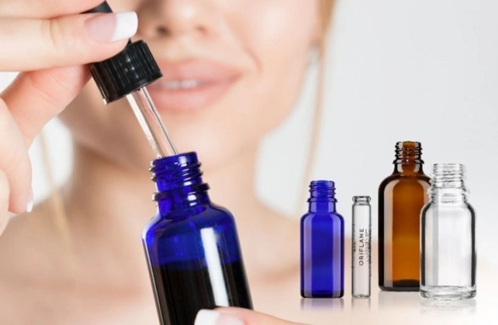 Woman holding a blue dropper bottle with various cosmetic bottles.