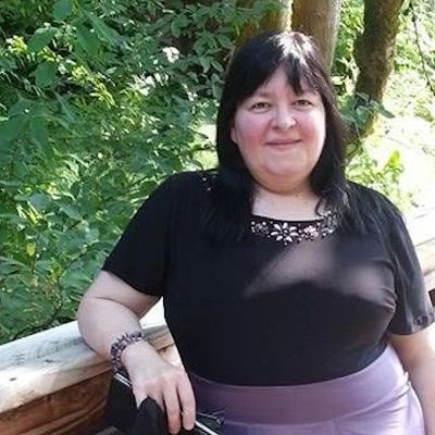 Woman smiling outdoors, leaning on a railing.