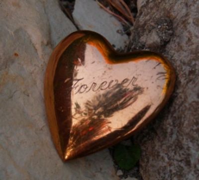 Heart charm on rocks engraved with the word, Forever.