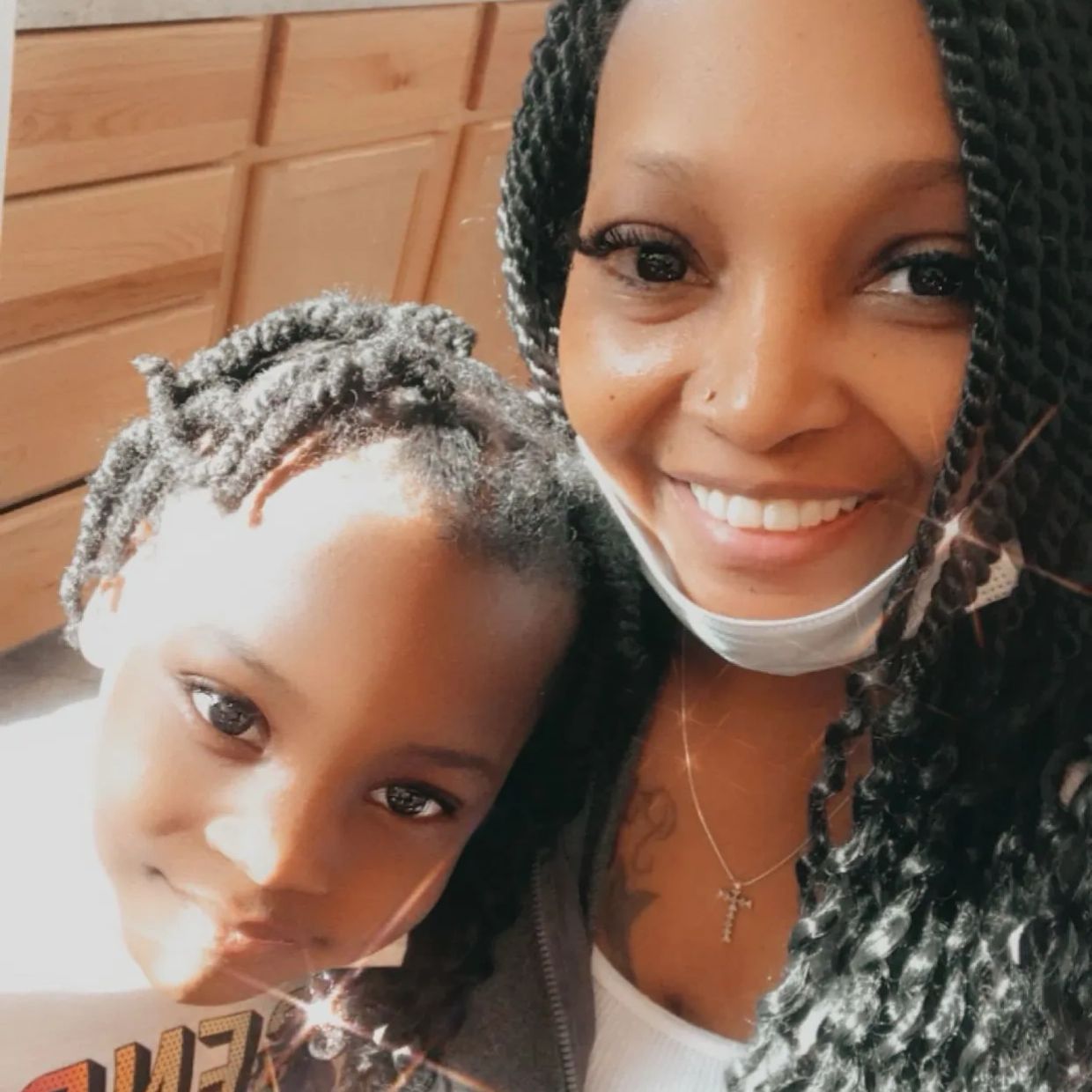 A smiling woman and child pose closely together for a warm selfie.