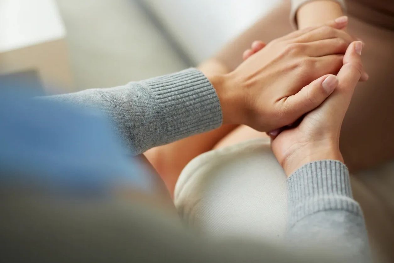Two people holding hands in a comforting gesture.