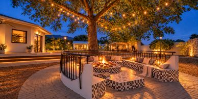 Cozy outdoor fire pit seating under a tree with string lights.