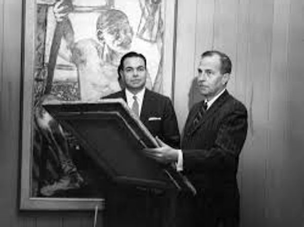 Two men in suits examining a framed artwork in a gallery setting.