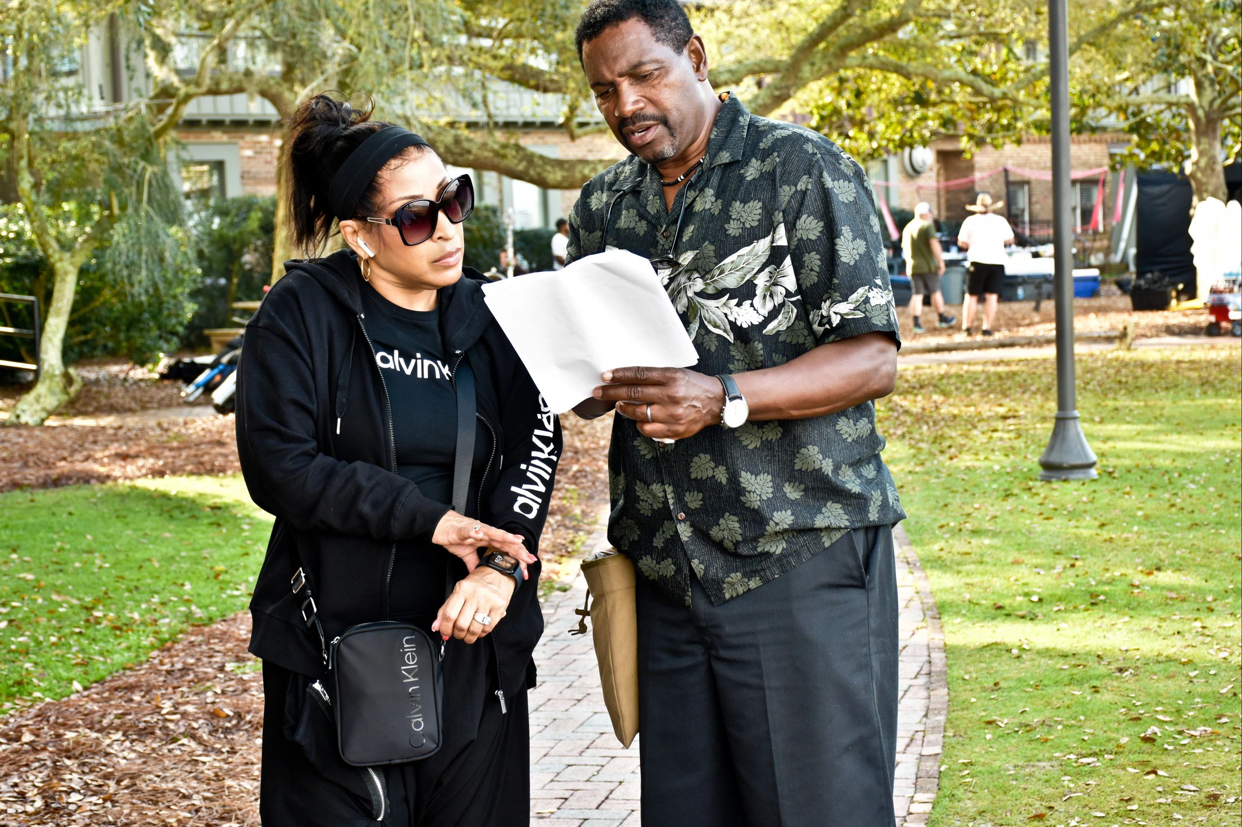 Two people reviewing a document outdoors in a park setting.