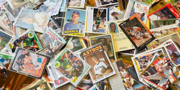 A scattered collection of vintage sports trading cards, mostly baseball and basketball.
