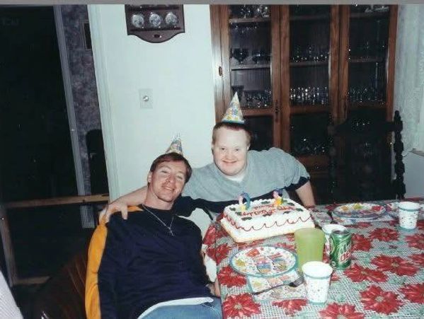 Two people wearing party hats celebrating a birthday with cake.