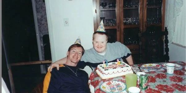 Two people wearing party hats celebrating a birthday with cake.