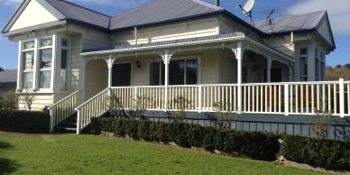 White house with a large porch and ramp.