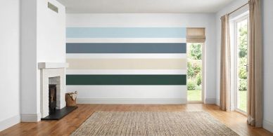 Empty room with striped accent wall and fireplace.