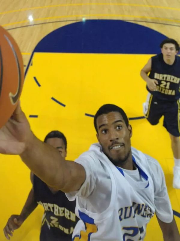 Basketball player in white jersey making a layup during a game.