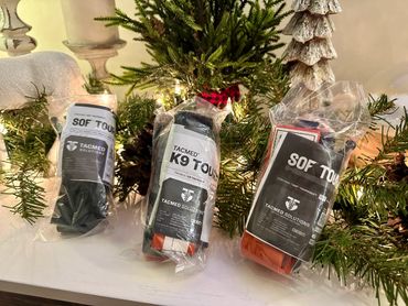 Three TACMED medical tourniquets displayed in holiday decor.