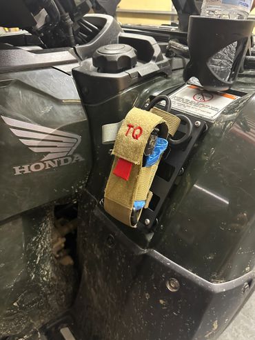 Close-up of a Honda ATV with a tactical pouch labeled 'TQ'.
