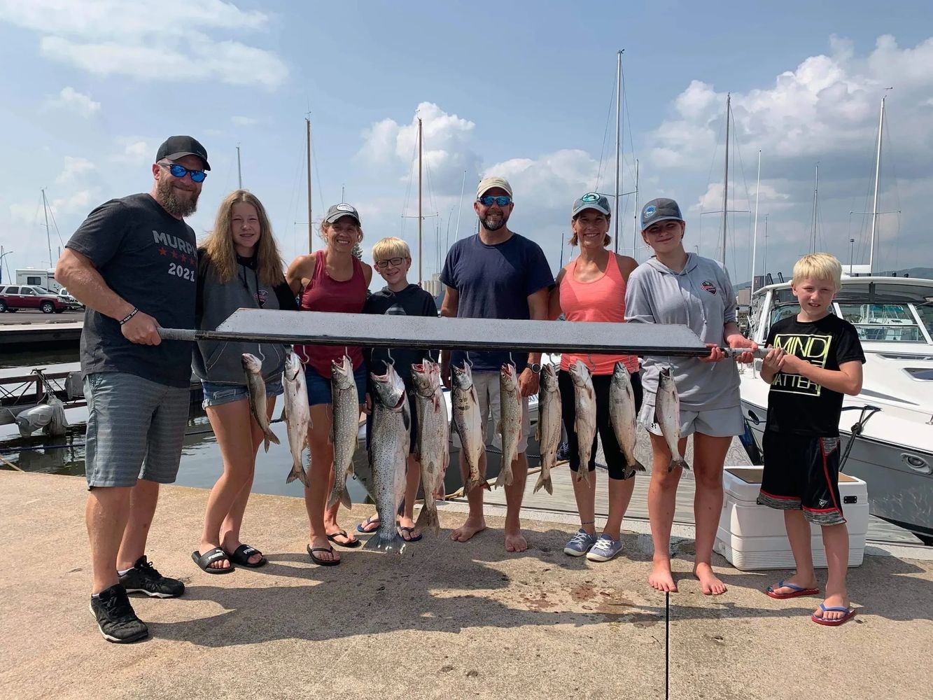 Group of people proudly displaying a large catch of fish at a marina.