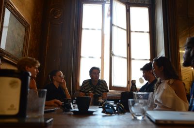 Group of young adults having a discussion around a table in a cozy room.