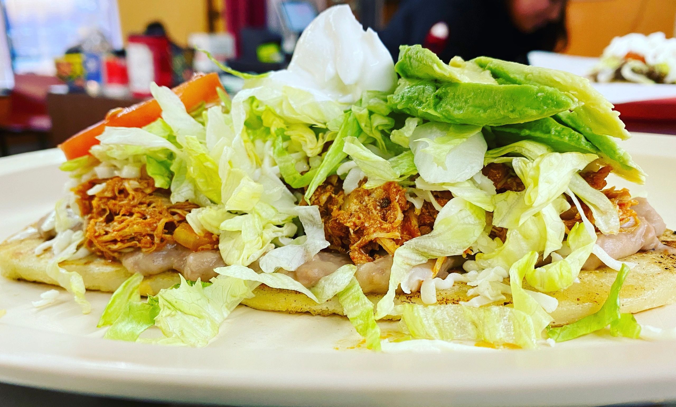 Huarache.
Made from corn masa. 
Cooked and then topped with beans, choice of meat, cheese, lettuce, 