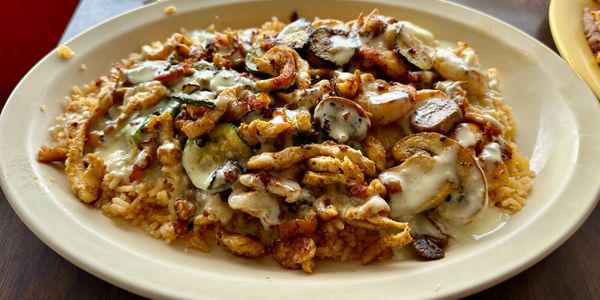 Grilled chicken on a bed of rice  topped with cheese dip.