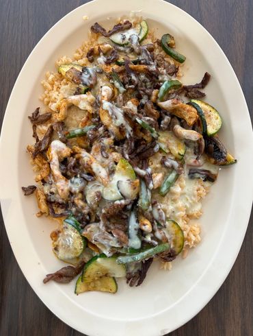 Plate of rice with veggies, beef, and melted cheese.