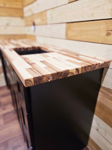 Close-up of a wooden countertop on a black cabinet in a rustic room.