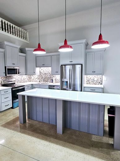 Modern white kitchen with island and red pendant lights.