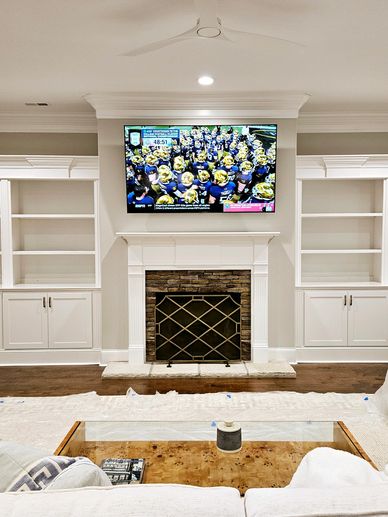 Modern living room with built-in shelves, fireplace, and wall-mounted TV.
