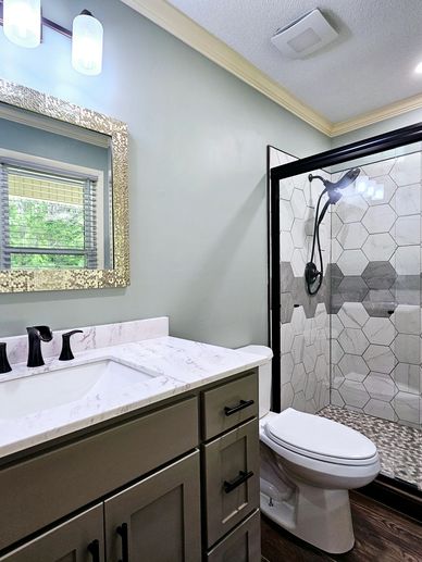Modern bathroom with marble countertop and hexagonal tile shower.