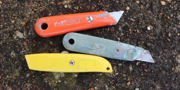Three brightly coloured Stanley knives on the ground