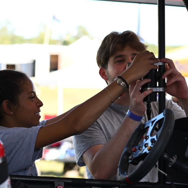 Two people adjusting equipment inside a vehicle.