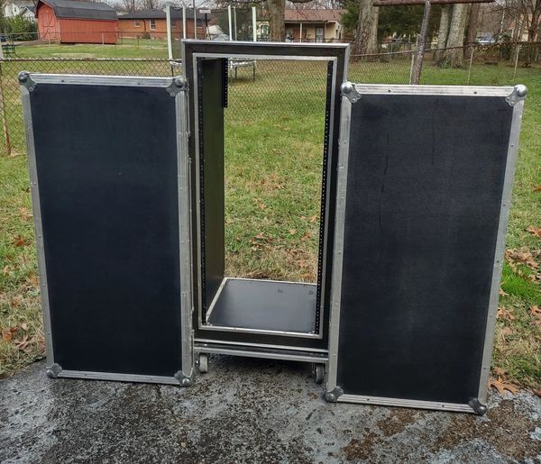 Open black equipment rack case with two detached panels outdoors.