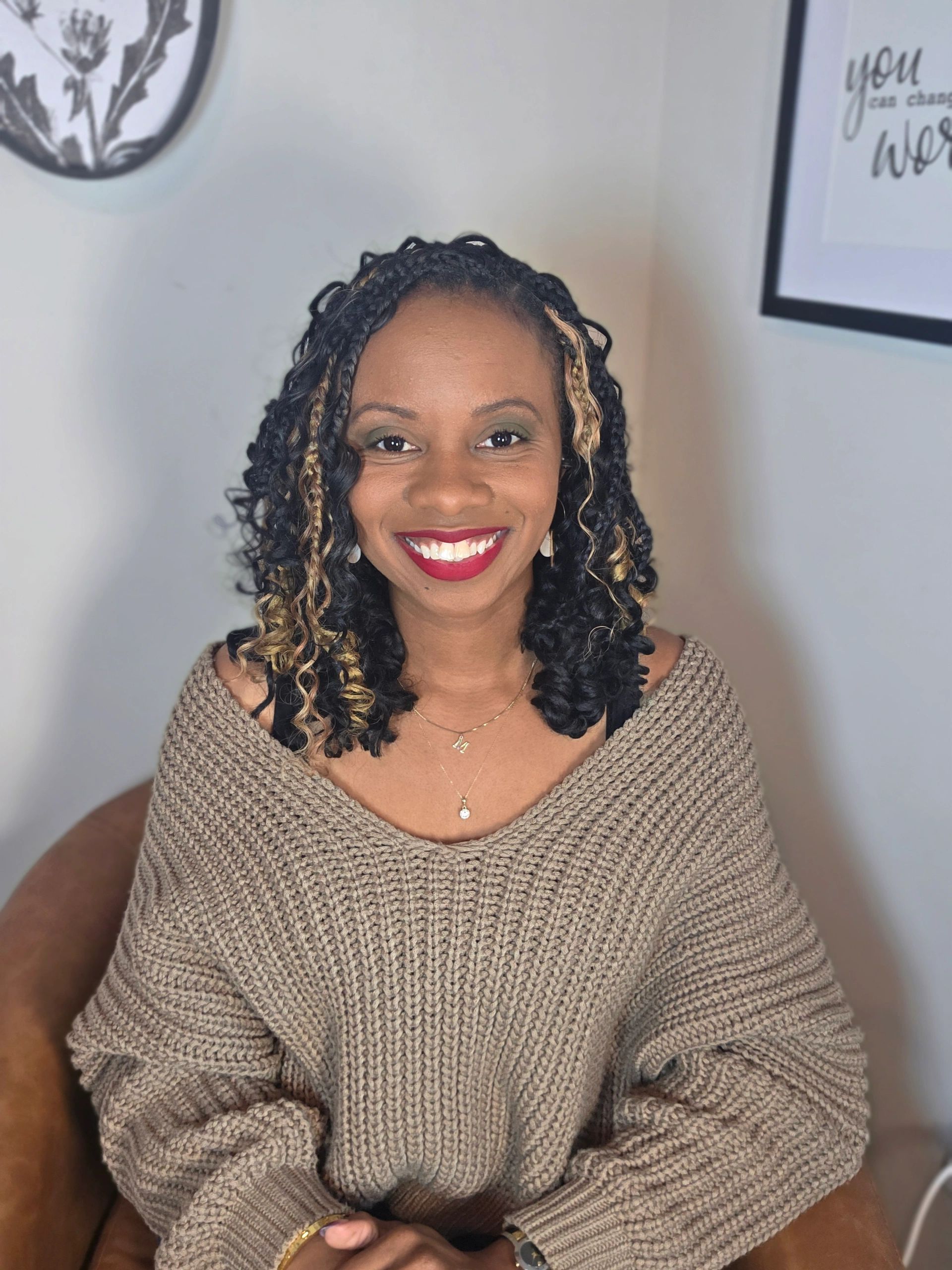 Smiling woman with curly hair and a cozy sweater.