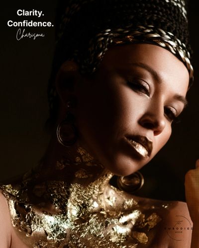 Elegant woman adorned with gold foil and braided hair, exuding confidence and charisma.
