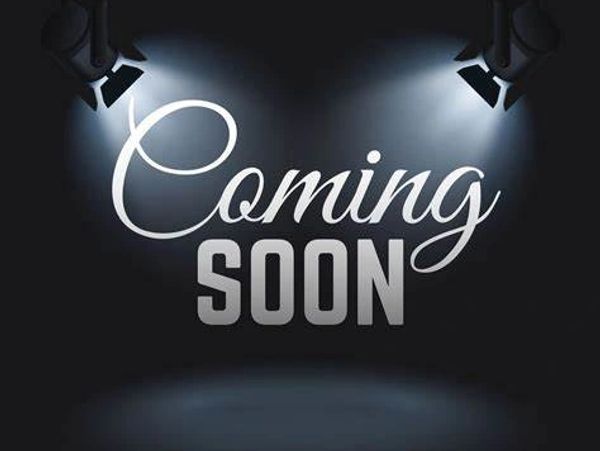 Spotlights illuminate the text 'Coming Soon' on a dark background.