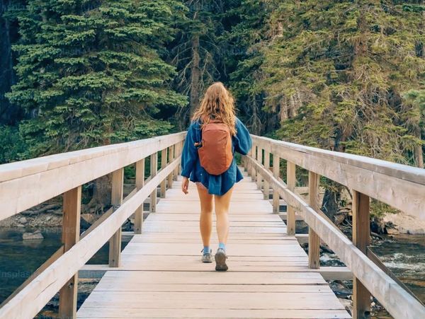 A female executive hiking along a wood bridge.