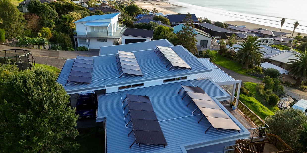 Modern house with solar panels on the roof near the beach.